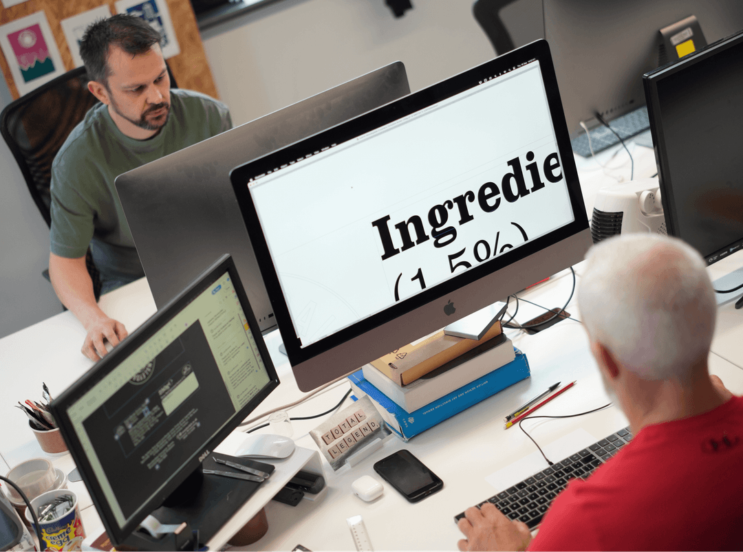 A professional focusing on a large computer screen displaying typography in a busy Dubai workspace.