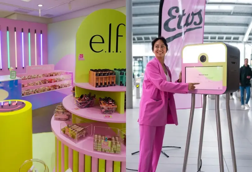 Woman in a pink suit using a digital kiosk at an Etos beauty pop-up store next to an elf cosmetics display.