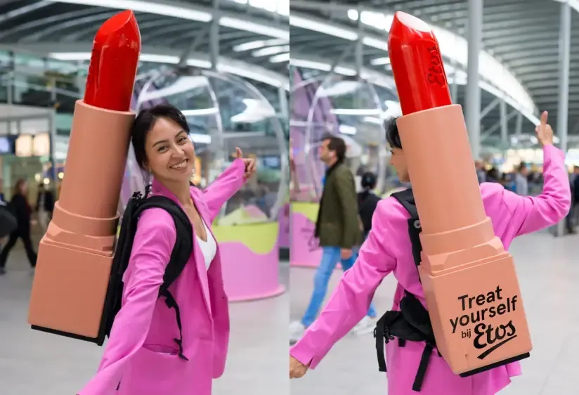 Promoter in a pink suit wearing a giant red lipstick backpack with "Treat yourself bij Etos" branding.