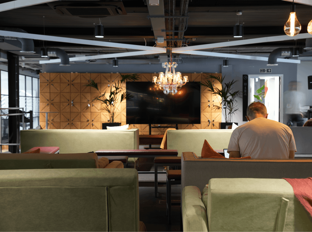 A stylish office lounge in Leeds with comfortable seating, a chandelier, and a large wall-mounted screen.