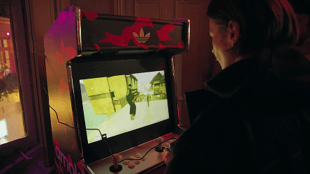 A person playing a custom-branded arcade machine at a launch event in a dimly lit room.