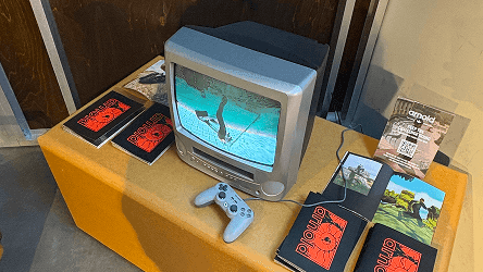 Retro TV and video game controllers displayed with Mike Arnold launch party merchandise.
