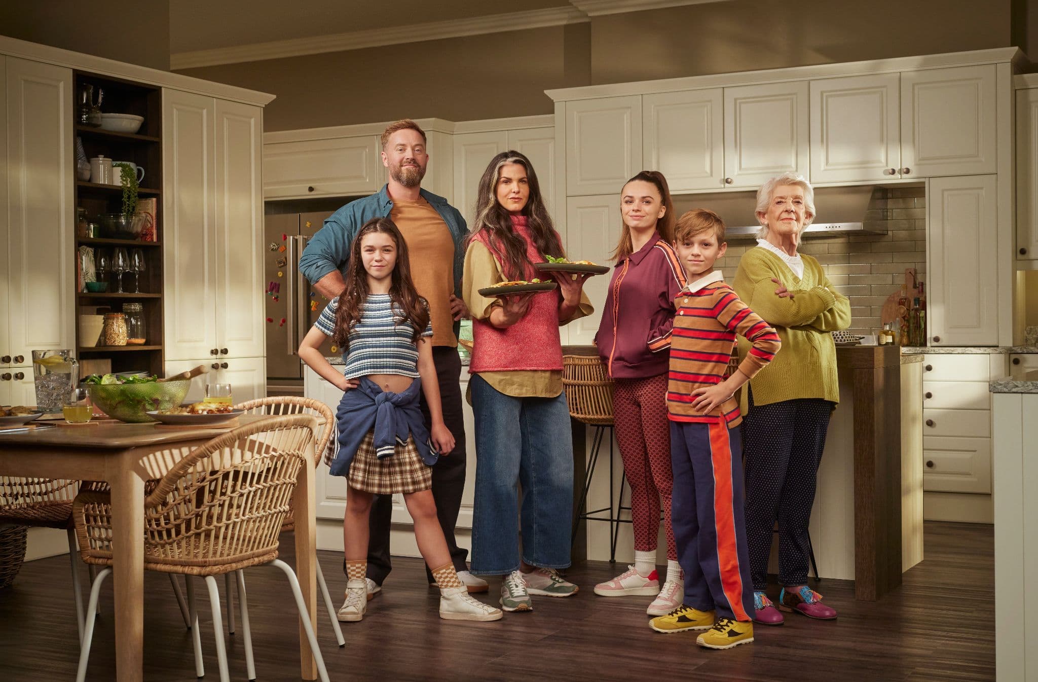 Multi-generational family standing confidently together in a spacious cream-colored traditional kitchen.