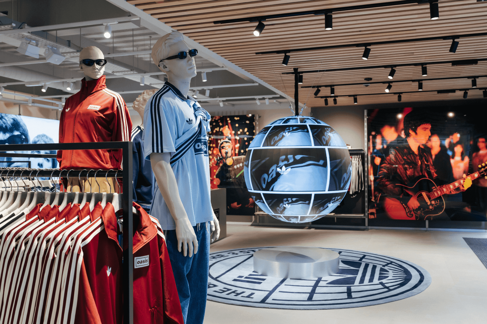 Mannequins styled in retro sportswear standing near a globe-shaped digital installation.