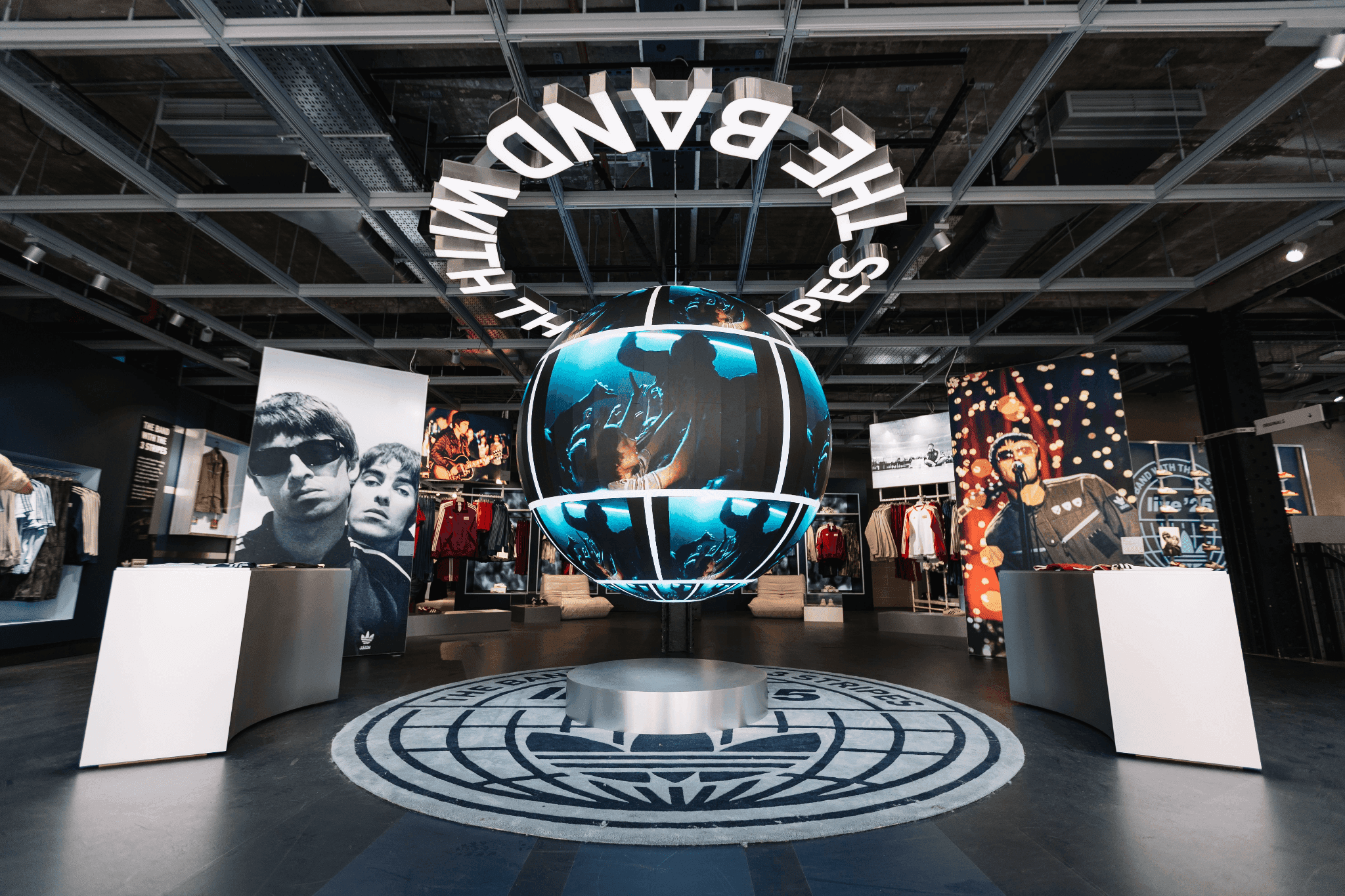 A circular overhead neon sign with "The Band With The 3 Stripes" above a gallery floor.