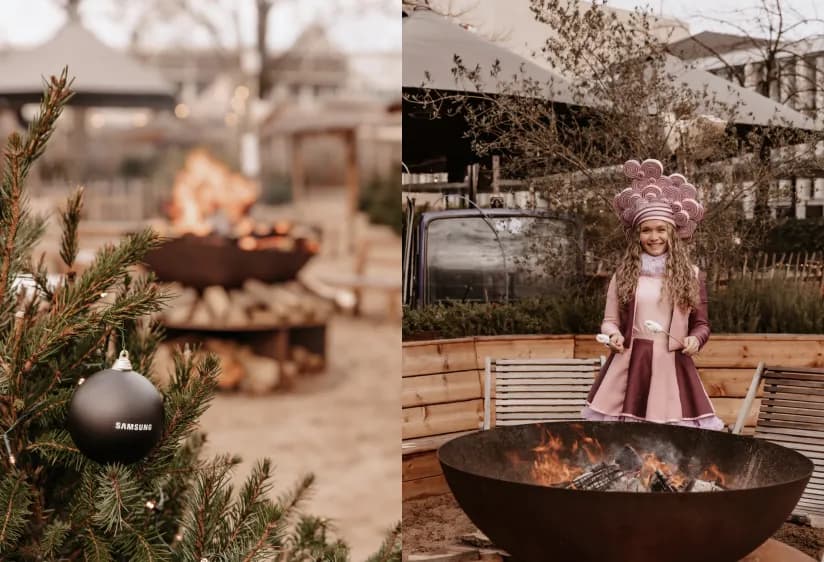Samsung branded Christmas bauble on a tree and a costumed performer roasting marshmallows over a fire.