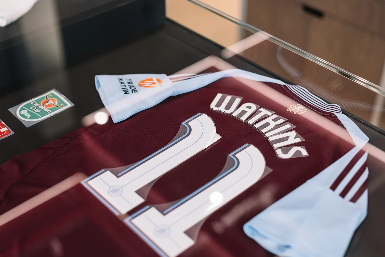 Close-up of an Aston Villa number 11 "Watkins" jersey displayed in a glass case with a Carabao Cup badge.