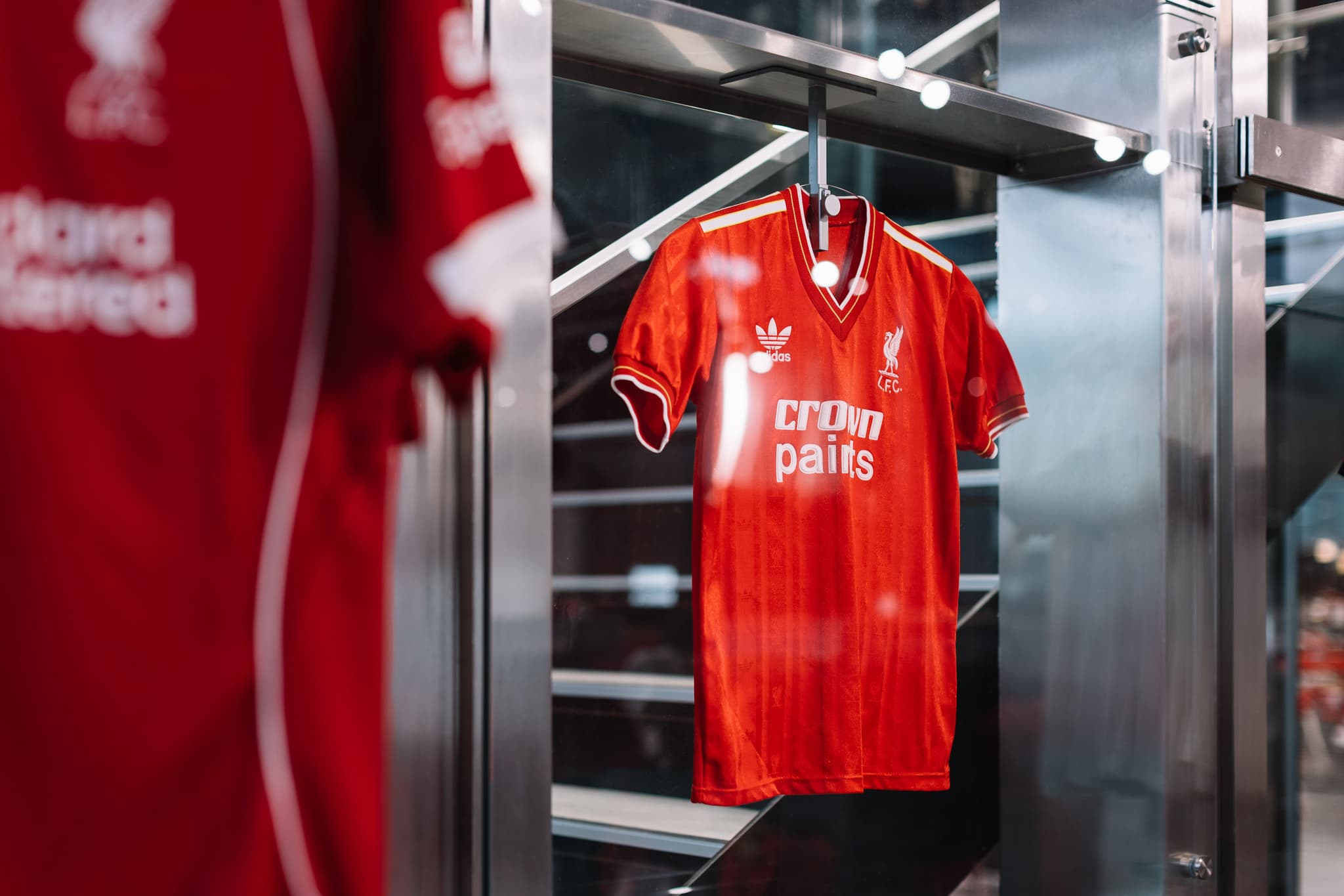 A vintage red Liverpool FC jersey with the Adidas logo displayed behind glass.